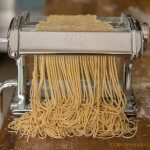 Cutting the noodle dough with the spaghettini-sized cutter to make homemade Chinese egg noodles from scratch